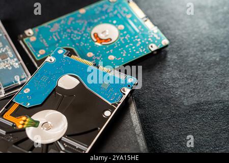 Close-up view of hard disk drives with blue circuit boards and metallic components, placed on a dark surface. The image showcases the intricate detail Stock Photo