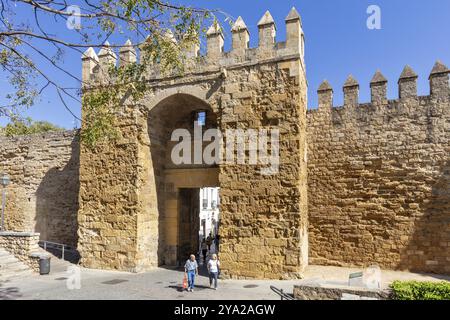 Massive historic city gate made of stone with people passing by in sunny weather, Cordoba Stock Photo