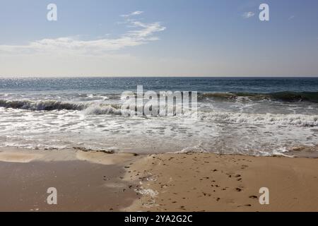 Gentle waves roll onto a deserted sandy beach under a blue sky, Tarifa Stock Photo