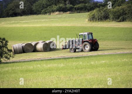 Tractor with hay bales in a meadow Stock Photo