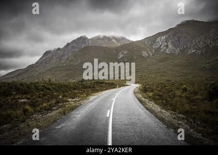 The picturesque Gordon River Rd at the Sentinel range of mountains near Bitumen Bones Sculpture on a cool wet summer's morning in Southwest National P Stock Photo