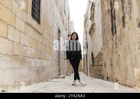 Portrait of a 29 year old standing Asian American girl, wearing a black leather vest and jeans Stock Photo