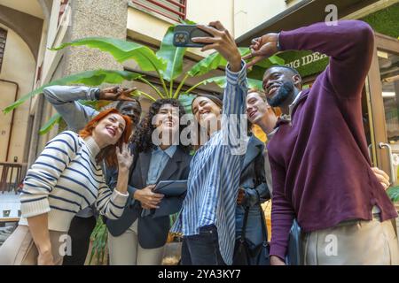 Colleagues gesturing success taking selfie in the patio of a coworking space Stock Photo