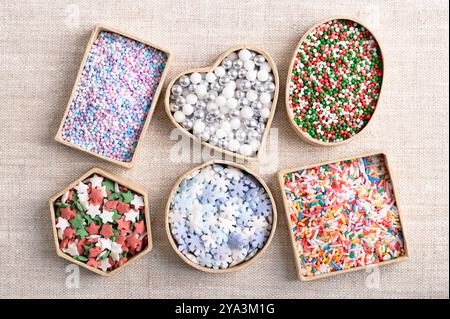 Colorful sugar sprinkles and nonpareils in small cardboard boxes over linen. Also known as hundreds and thousands, jazzies, jimmies, and vermicelli. Stock Photo