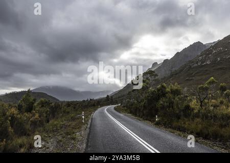 The picturesque Gordon River Rd at the Sentinel range of mountains near Bitumen Bones Sculpture on a cool wet summer's morning in Southwest National P Stock Photo