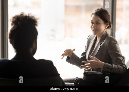 Happy young business woman in formal jacket talking to partner Stock Photo