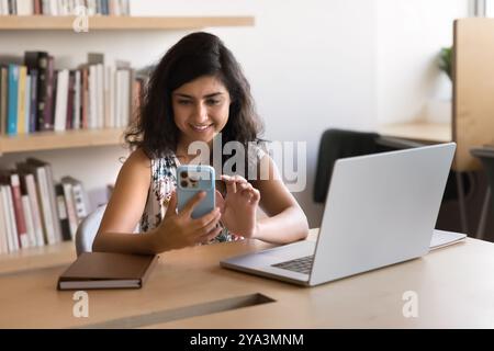 Positive young Indian businesswoman in casual using smartphone Stock Photo