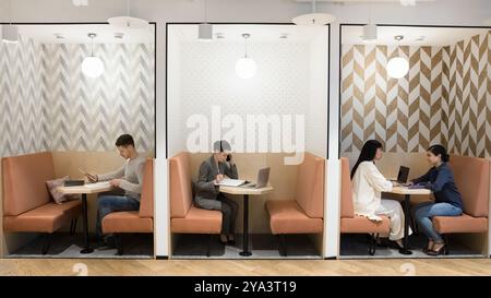 Multiethnic freelancers working in separate booths in modern freelance co-working Stock Photo