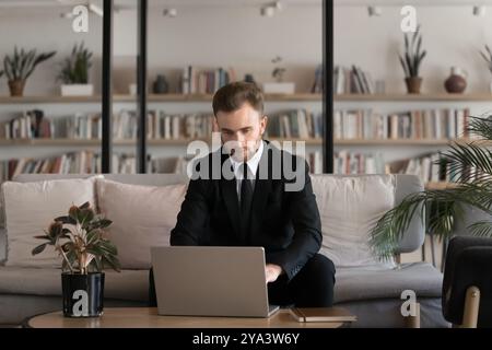 Serious young businessman in suit and tie working at laptop Stock Photo