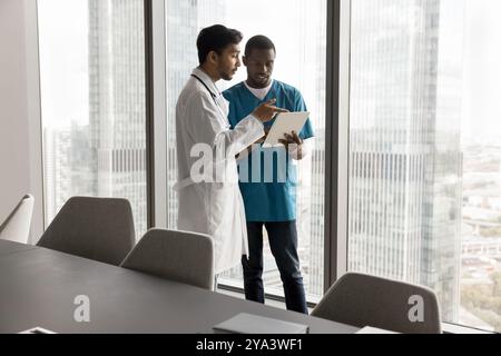 Attending physician instruct nurse at modern clinic office using pad Stock Photo