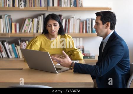 Multiethnic couple of business colleagues working at laptop together Stock Photo
