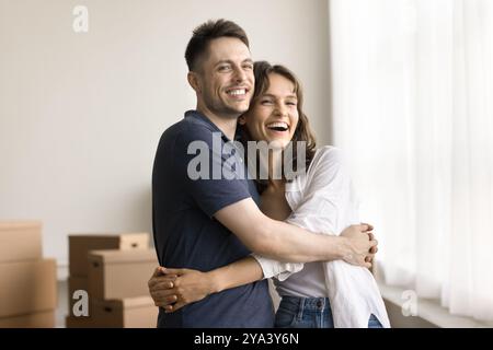 Portrait happy young couple hugging at living room with boxes Stock Photo