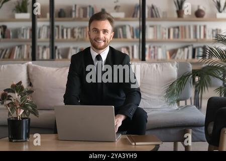 Happy successful young businessman using laptop in modern co-working Stock Photo