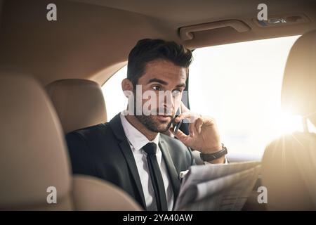 Businessman, newspaper and reading in transport with phone call for career, meeting or conversation. Male person, car and commute on mobile tech as Stock Photo