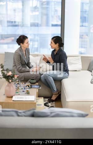 Diverse young office female friends talking in lounge zone Stock Photo