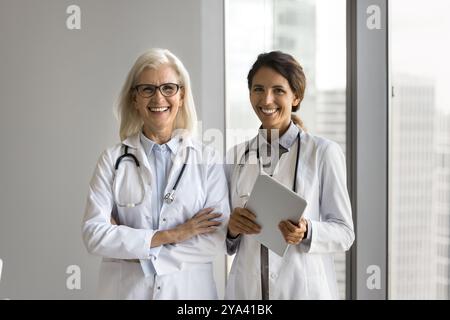 Two female doctors standing in white coats looking at camera Stock Photo