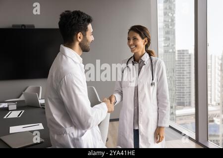 Young man woman medics coworkers shake hands after successful partnership Stock Photo