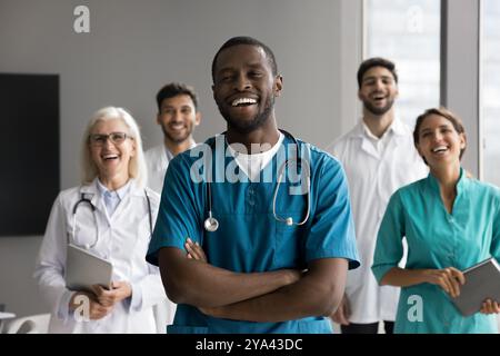Laughing young Black male surgeon stand before multicultural medics group Stock Photo