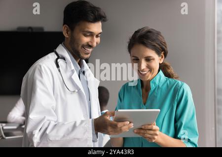 Skilled millennial male medic consult female colleague using tablet pc Stock Photo