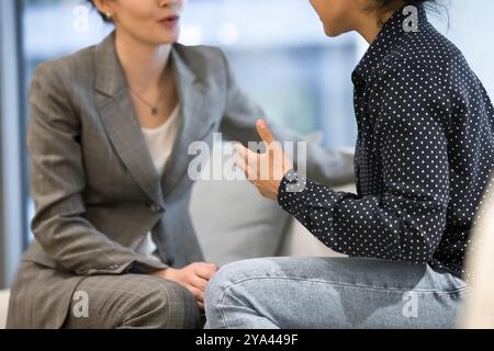 Female office employees sitting on office couch, talking, discussing tasks Stock Photo