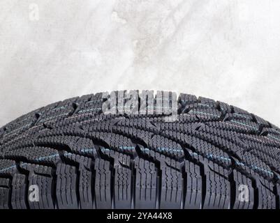 Car Parts - Closeup fragment tread new car winter tire on the background of a concrete wall Stock Photo