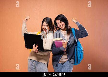Celebrating Academic Success Two Students Smiling with Their Books and Laptop Stock Photo