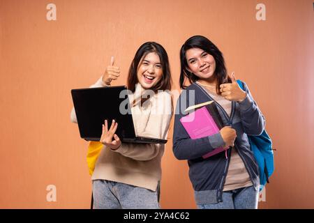 Two Joyful Students Celebrate Their Academic Success with Laptops and Books Stock Photo