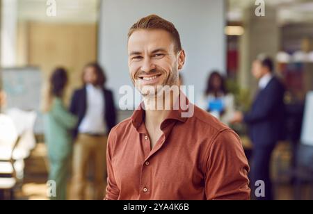Happy smiling young business man looking cheerful at the camera and smiling in office. Stock Photo