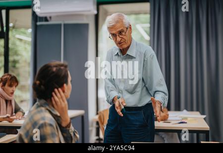 Elderly professor engaging with students in classroom setting Stock Photo