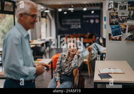 Students engaging with elderly professor in a modern classroom setting Stock Photo