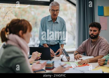 University students collaborating with senior professor on academic project Stock Photo
