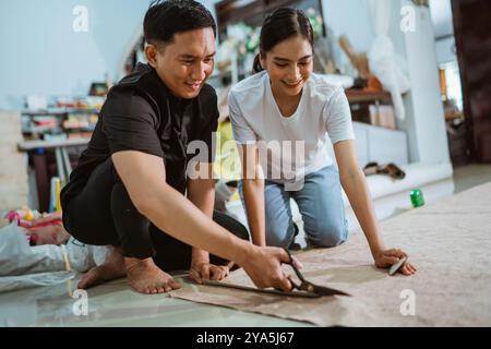 couple of asian production crew cutting the fabric using the fabric scissor Stock Photo