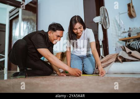 couple of asian production crew measuring the fabric using the measurement tape Stock Photo