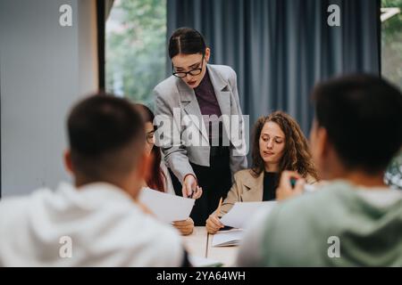 Teacher guiding students in classroom during group study session Stock Photo