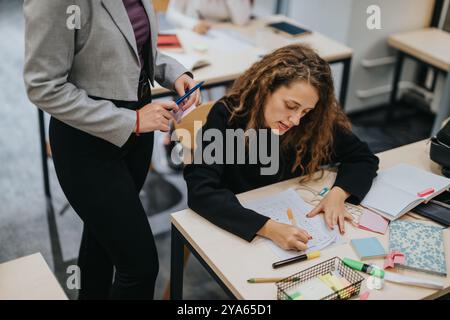 Teacher assisting student with notes in classroom setting Stock Photo
