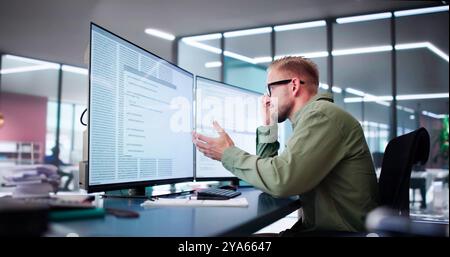 Unhappy Sad Developer Programmer Man In Stress Coding Software On Computer Stock Photo