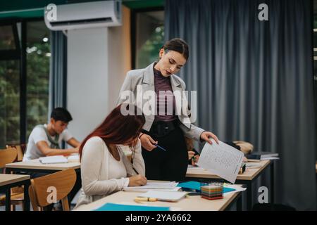Teacher assisting students in a bright classroom setting Stock Photo