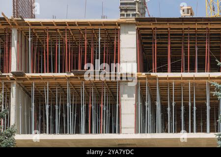 An apartment building under construction, showing the use of steel flashings and wooden beams for formwork on one side Stock Photo