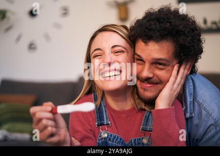 Cheerful smiling young Caucasian couple looking at positive pregnancy test result. Expecting baby. Stock Photo