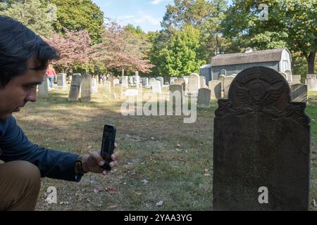 Sleepy Hollow, New York, USA. 12th Oct, 2024. A tourist takes a photo of the grave of Catriena Ecker van Tessell, said to have been the inspiration for Katrina van Tassell in Washington Irving's The Legend of Sleepy Hollow on the grounds of the Old Dutch Church in Sleepy Hollow on October 12, 2024 in New York. Sleepy Hollow, the setting for Washington Irving's iconic short story, is famous for its October street fair, its festive decorations and other vibrant Halloween celebrations and is expecting an influx of tourists through Halloween. (Credit Image: © Bryan Smith/ZUMA Press Wire) EDITO Stock Photo