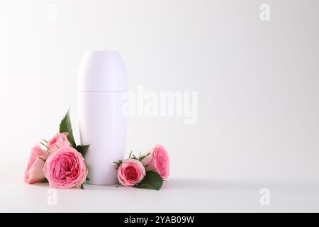 Roll-on deodorant and beautiful rose flowers on white background, space for text Stock Photo