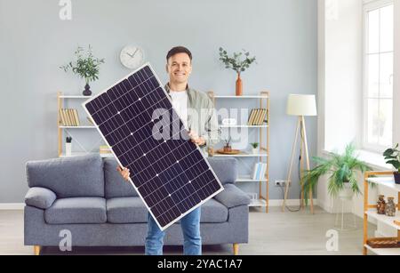Portrait of a happy, smiling man holding a modern sustainable photovoltaic solar panel Stock Photo