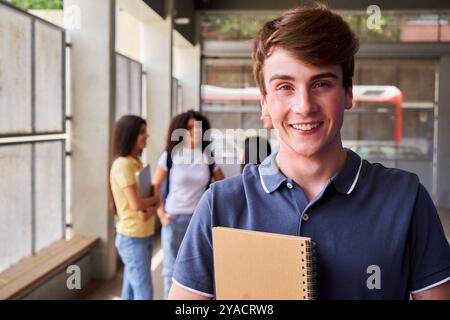 Cheerful portrait of a male high school student looking at camera smiling after class. Stock Photo