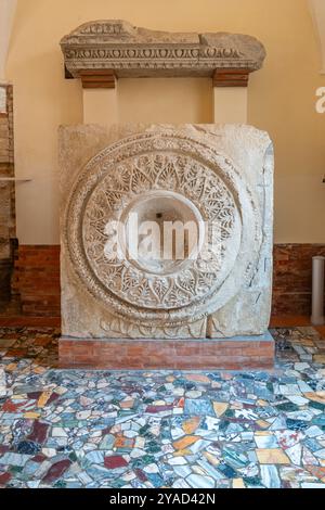 Ancient piece of marble in ruins carved with floral motifs inside a circle Stock Photo