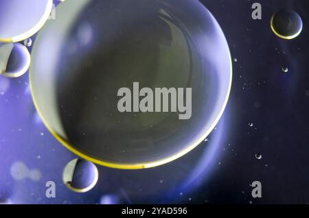 Close-up of iridescent oil streaks on water, with a smooth dark gradient background. Stock Photo