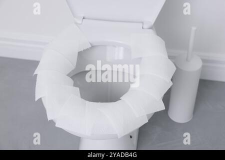 Toilet seat with paper tissues in bathroom Stock Photo