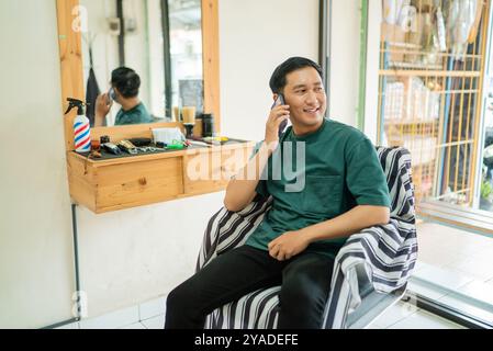 A man is in a barber shop talking on a cell phone Stock Photo