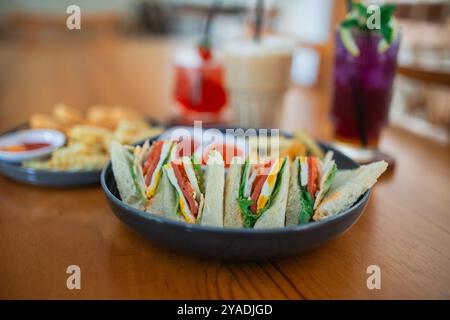 sandwich on a black plate with other menu items on a table in a cafe Stock Photo