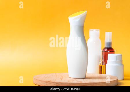 A sleek, white cosmetic bottle with a yellow cap, placed on a wooden surface. In the background, various other cosmetic bottles are visible against a Stock Photo