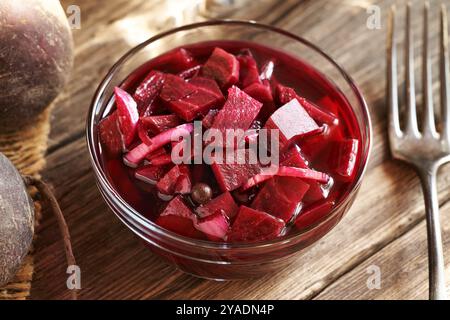A bowl of fermented red beet kvass in a glass bowl with a fork on a wooden table Stock Photo